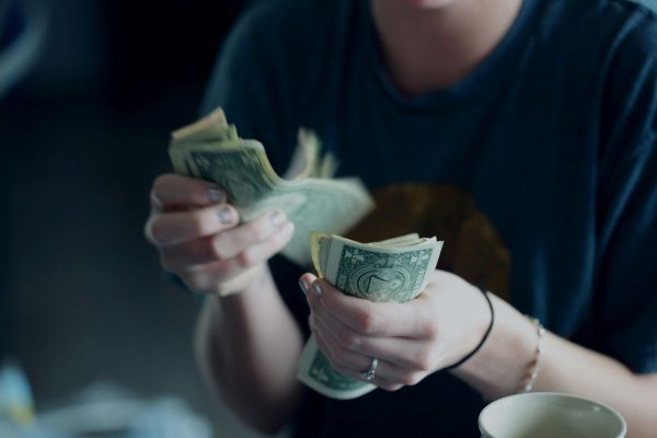 Person counting cash by hand, illustrating the process of calculating life insurance returns and evaluating the long-term value of an insurance policy.