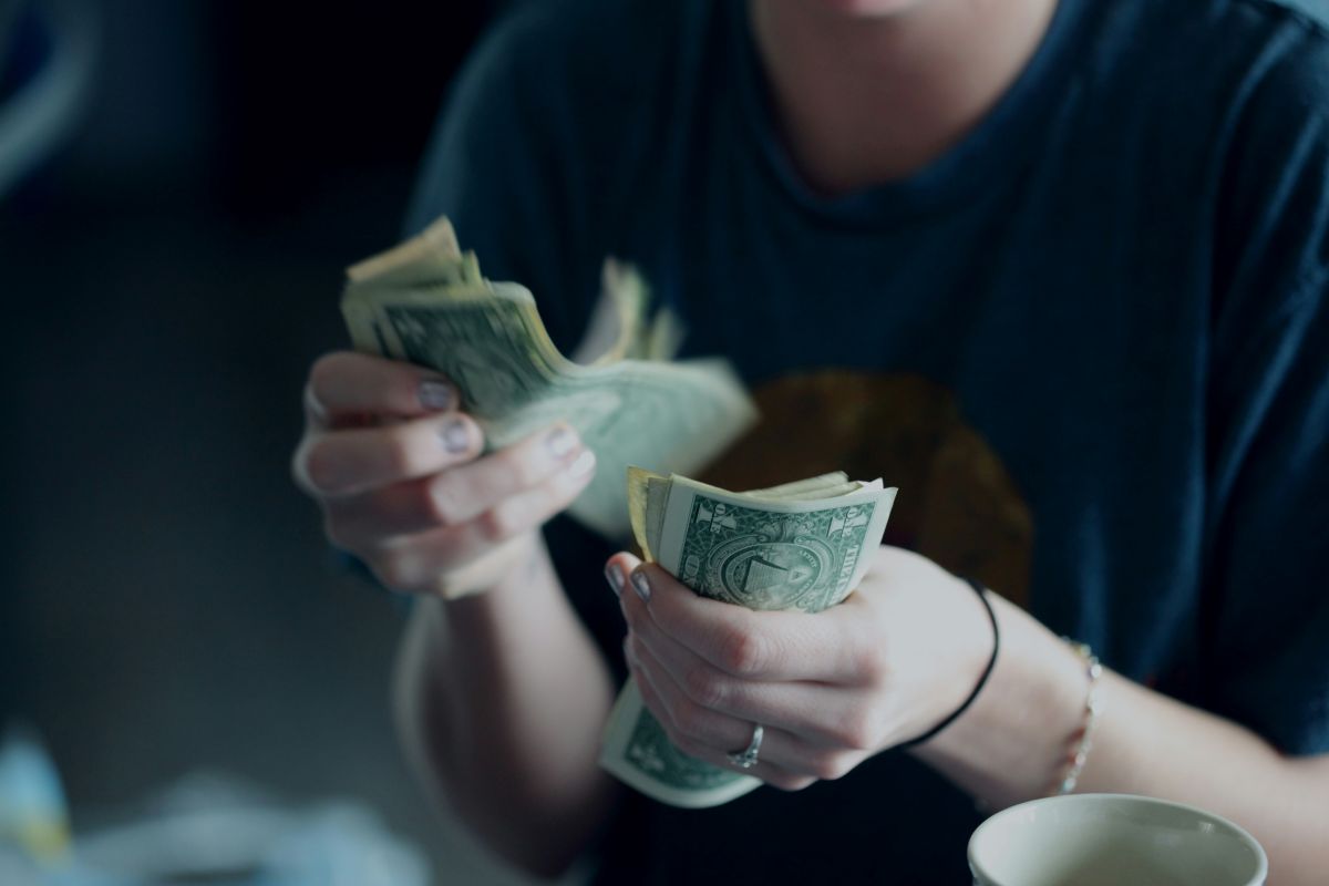 Person counting cash by hand, illustrating the process of calculating life insurance returns and evaluating the long-term value of an insurance policy.