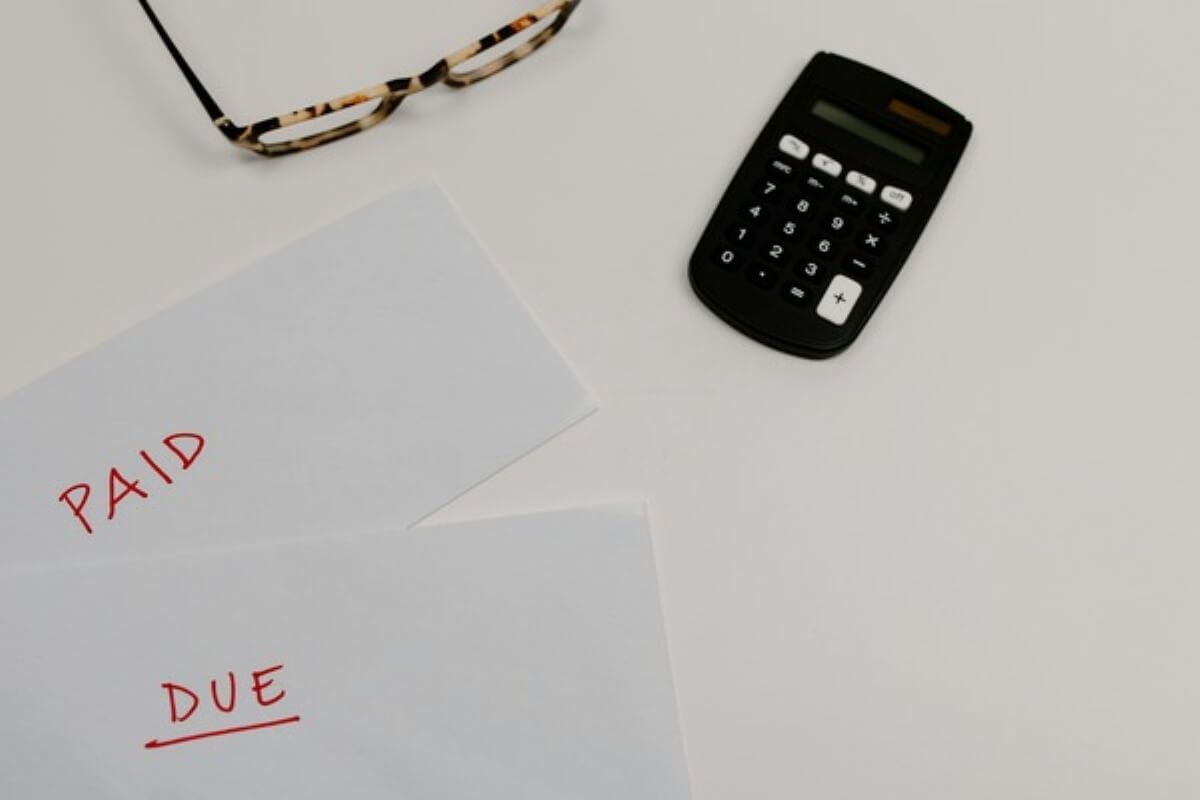 Paid and due bills beside a calculator, highlighting the importance of budgeting for student loans and repayment alongside monthly expenses.