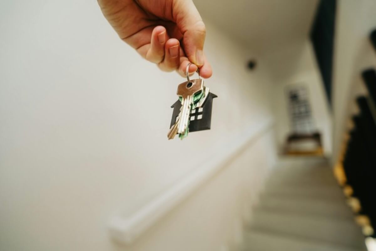 Hand holding house keys inside a new home, symbolising choosing between an HDB loan and a bank loan before collecting your keys.