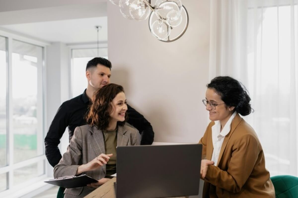 Homebuyers discussing financing options with a property consultant before deciding between an HDB loan and a bank loan.