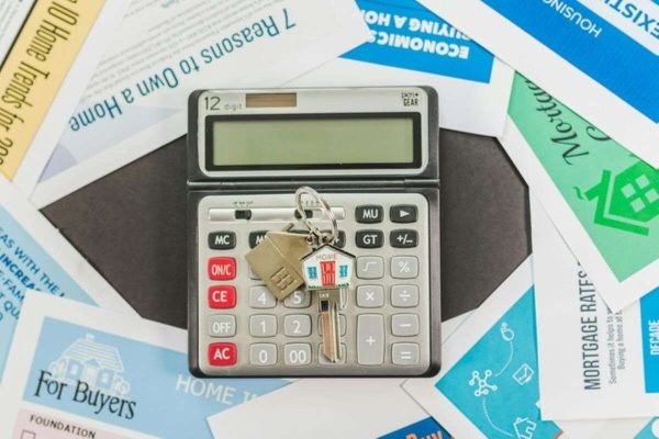 Calculator and house keys on home buying guides, comparing an HDB loan and a bank loan for first-time homebuyers.