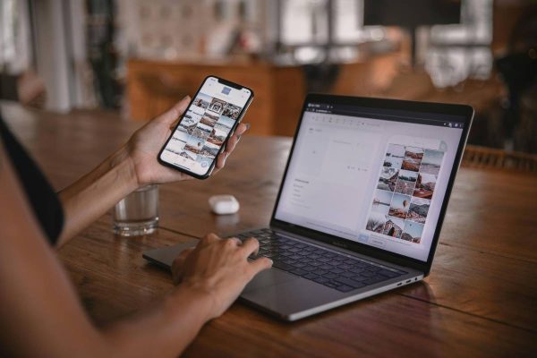 Finance content creator using a smartphone and laptop to produce personal finance content for social media.