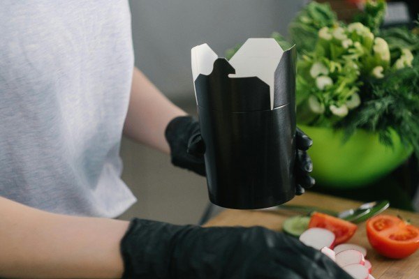 Person packing takeaway food in a kitchen, showcasing one of the affordable home business ideas for starting a food business from home.