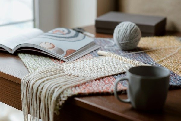 A yarn, magazine, and a mug on top of the table.