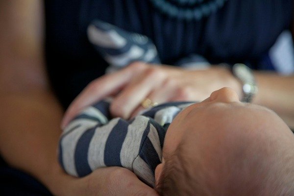 Close-up of a person gently holding a baby in their arms