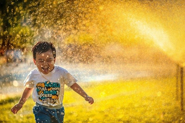 Boy running through water spray on a sunny day