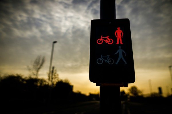 Pedestrian and cyclist traffic light showing red signals against a sunset background