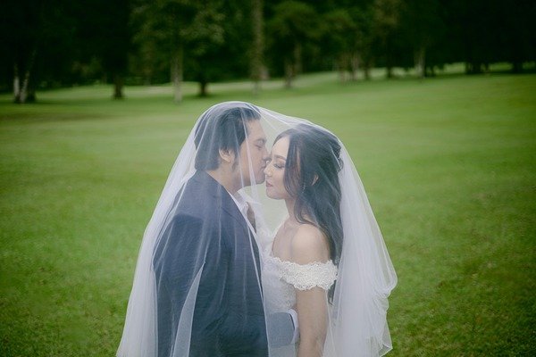 A newly-wed couple kissing outdoor