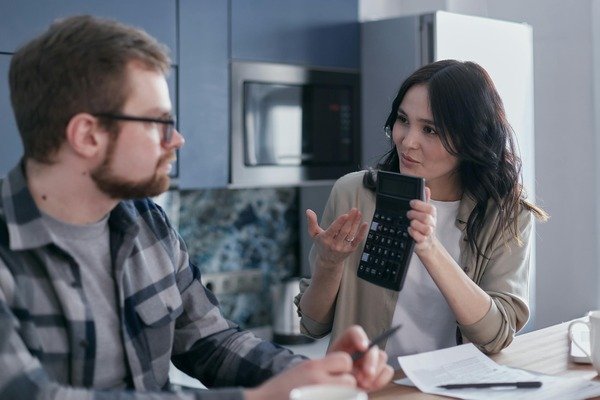 A couple sitting on a table discussing while the woman is holding a calculator