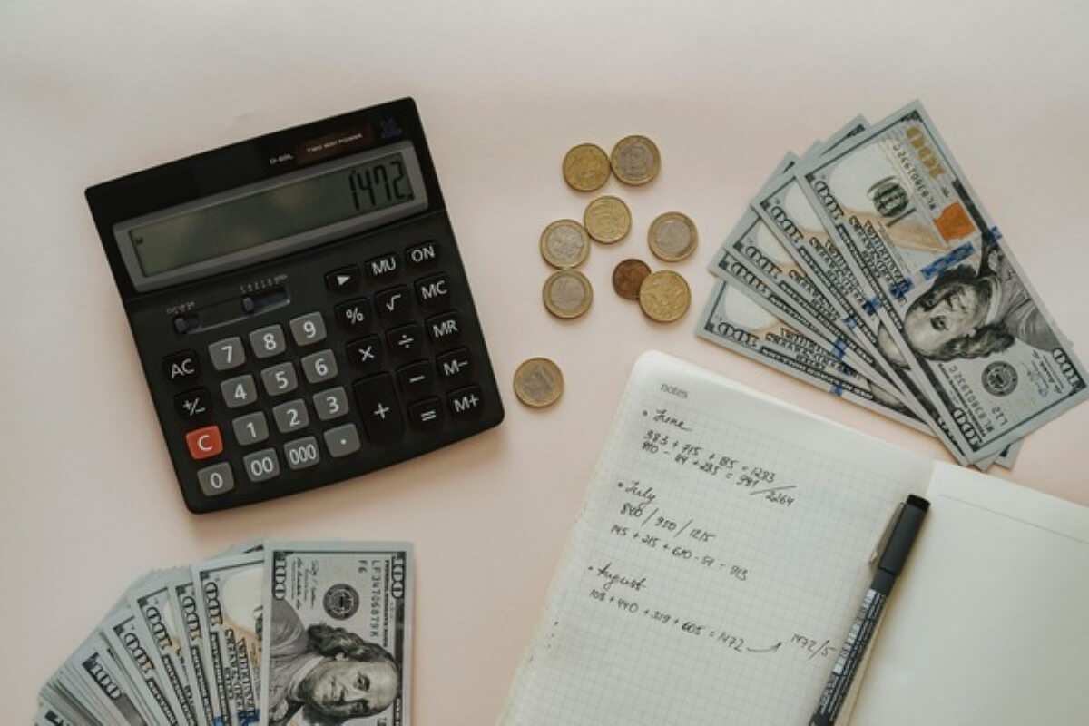 Calculator, cash, and budgeting notes used to estimate costs and finances for buying property in Malaysia.