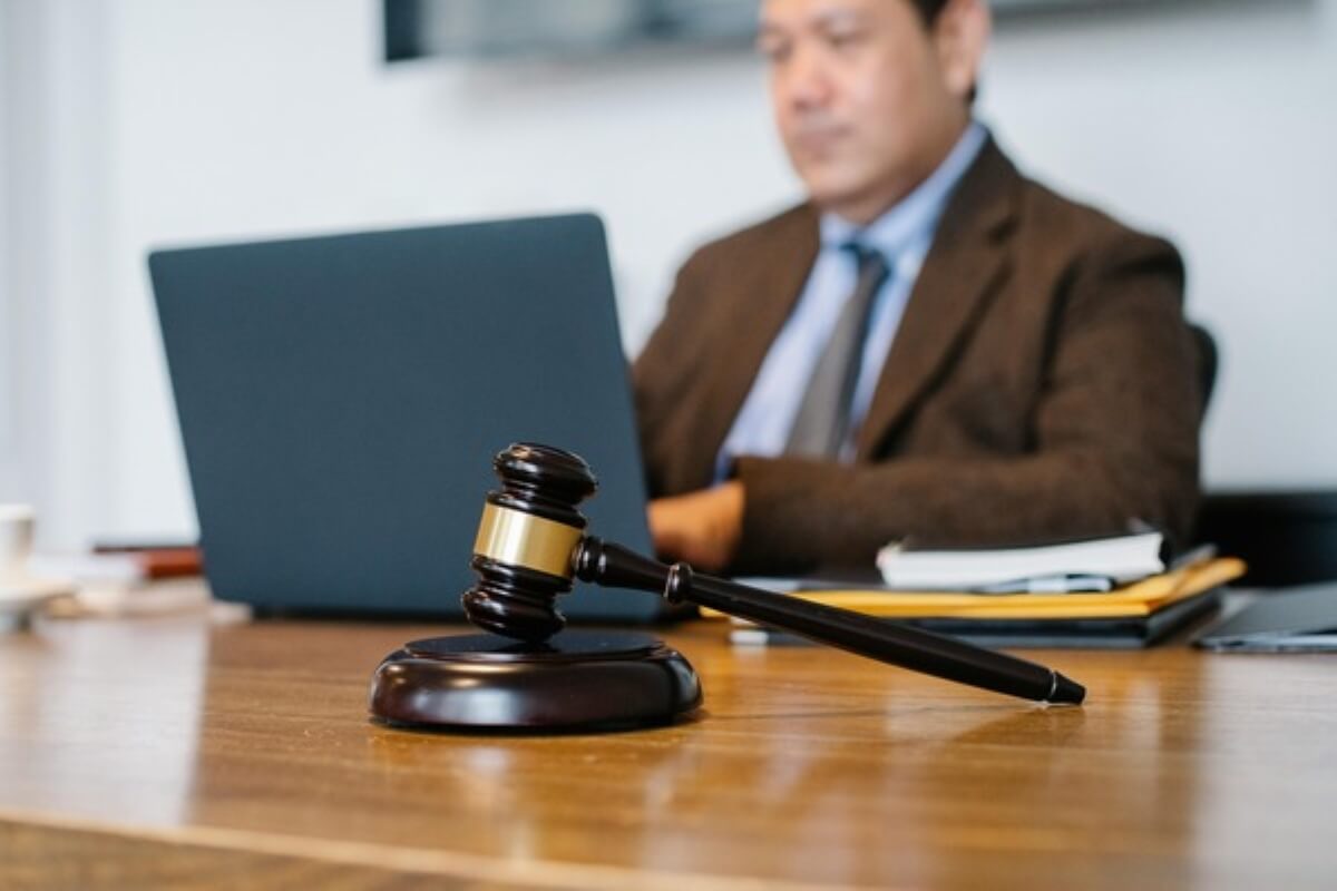 Judge's gavel beside a lawyer working on a laptop, highlighting the legal considerations of buying property in Malaysia.