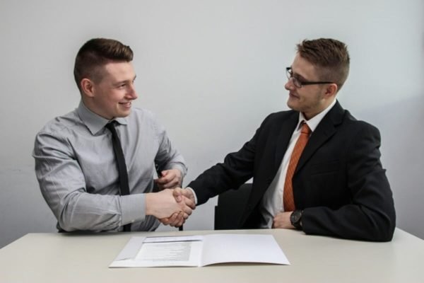Two professionals shaking hands after agreeing on the terms of a contract job.