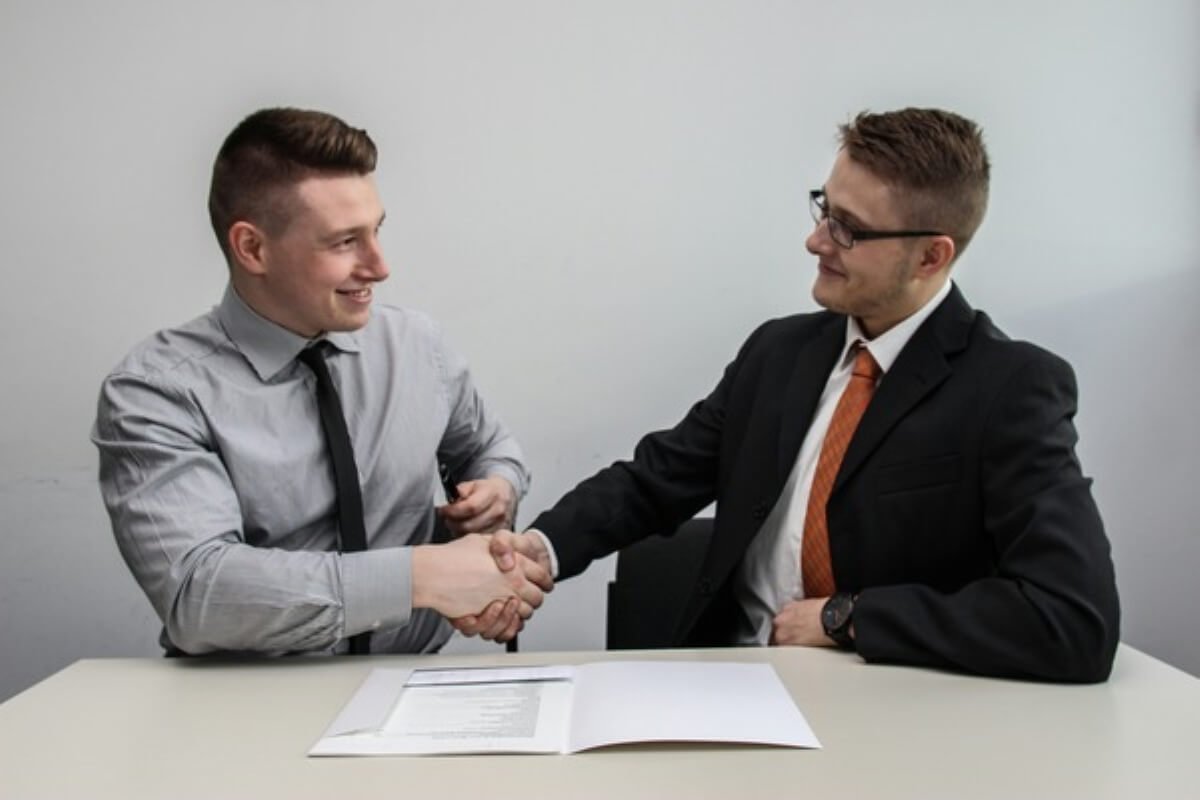 Two professionals shaking hands after agreeing on the terms of a contract job.