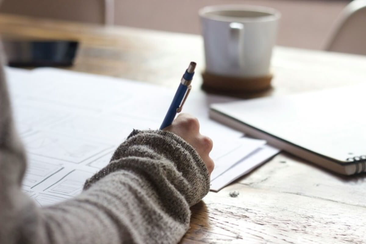 Person taking notes and planning tasks to stay organised and productive in contract jobs.
