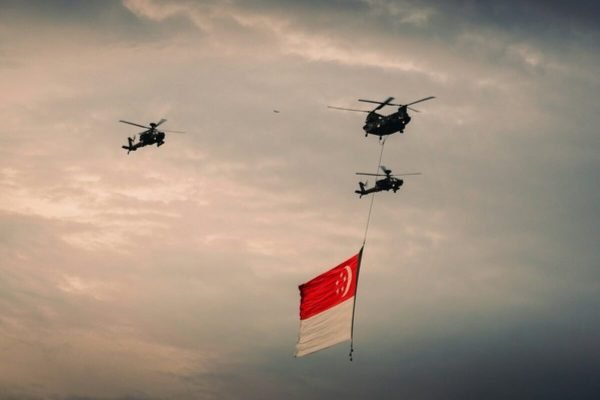 Singapore flag displayed during a military flypast, representing national service and the connection between MINDEF SAF and term life insurance benefits.