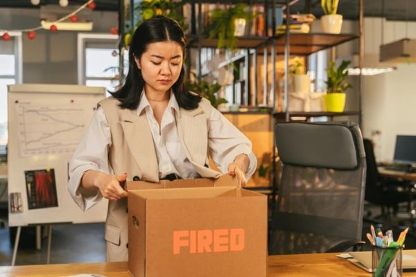 Employee packing belongings after being laid off, highlighting financial tips after job loss such as budgeting, cutting expenses, and planning the next career move.