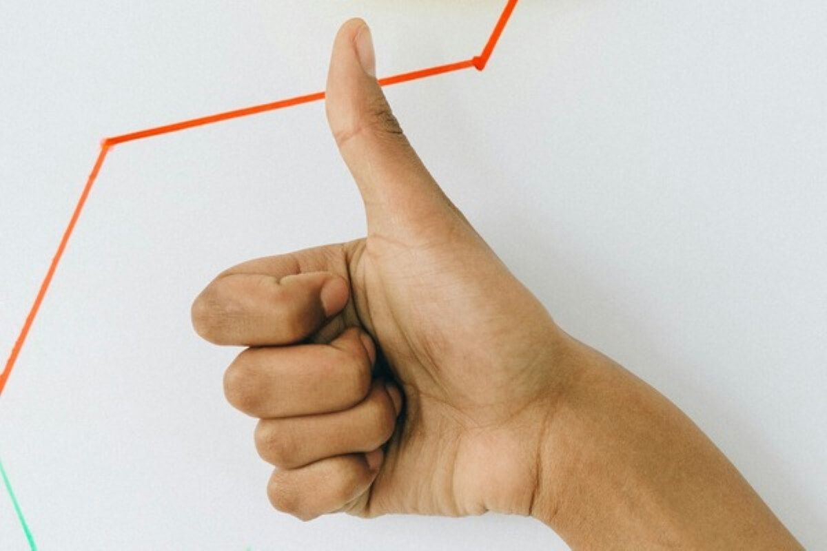 Thumbs-up in front of an upward-trending graph, symbolising business growth and success as you grow your side hustle into a business.