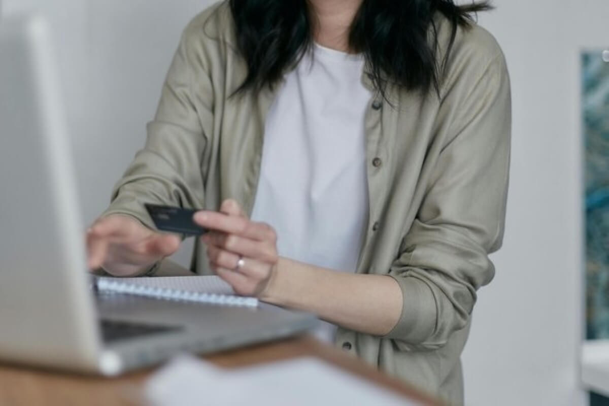 Person using a credit card to compare policies online before buying insurance.