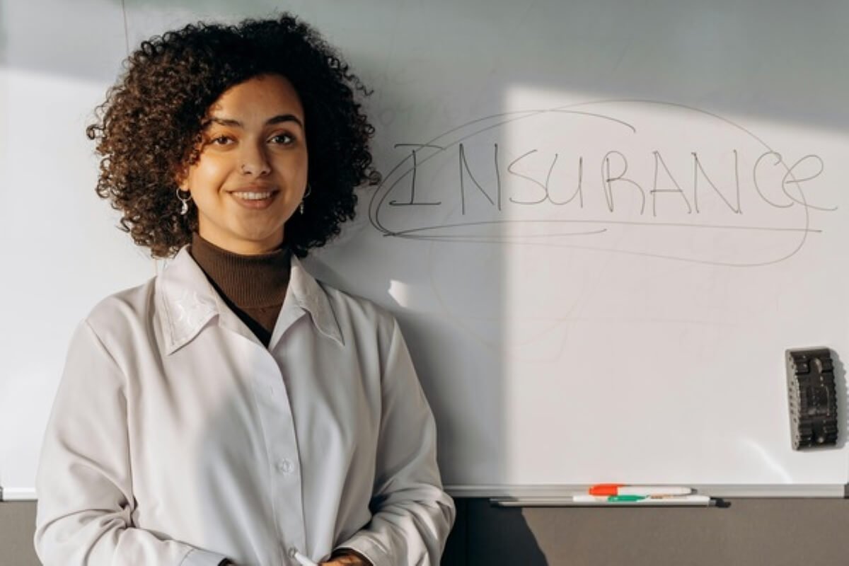 Insurance adviser standing beside a whiteboard, explaining policy options for buying insurance.