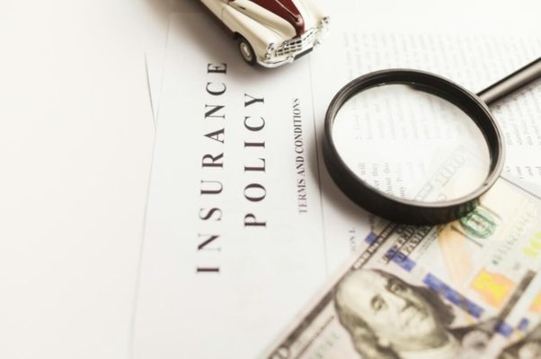 Insurance policy document with a magnifying glass and model car, illustrating common types of insurance in Singapore such as motor insurance.
