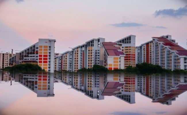 Singapore HDB blocks reflected in water, representing mortgage loan insurance for public housing homeowners.