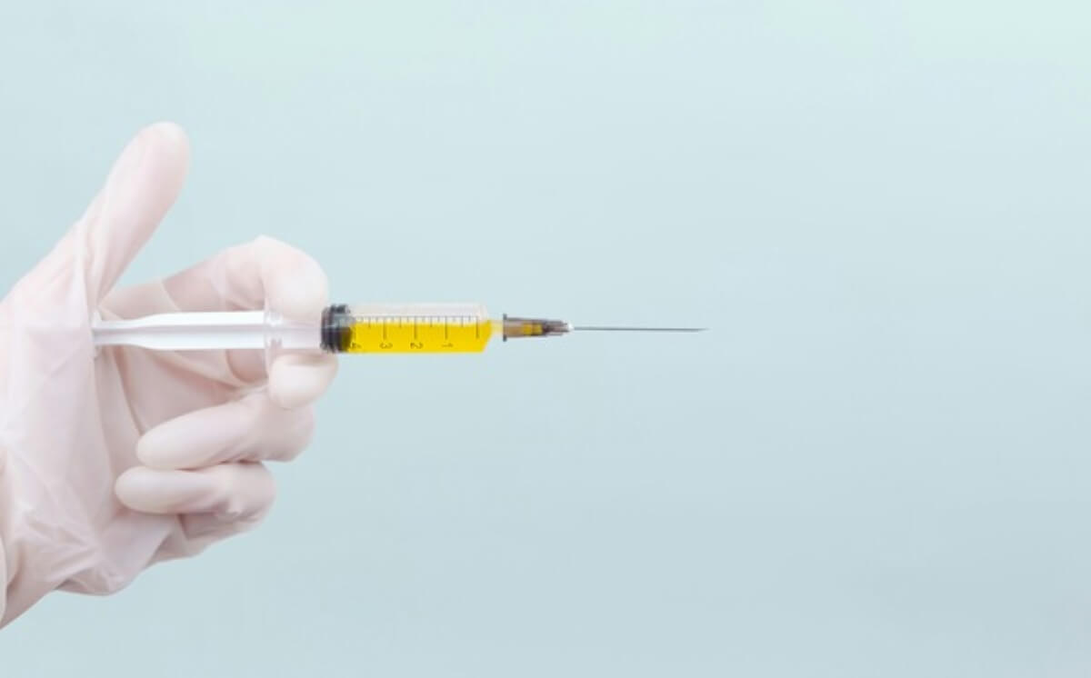 Gloved hand holding a syringe, representing injectable weight loss drugs prescribed for obesity and diabetes management.