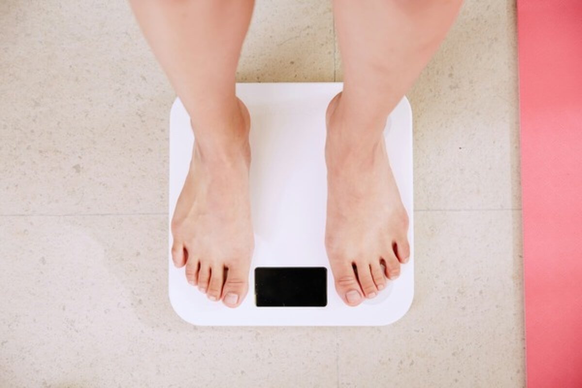 Person standing on a weighing scale to monitor progress while using weight loss drugs as part of a weight management plan.