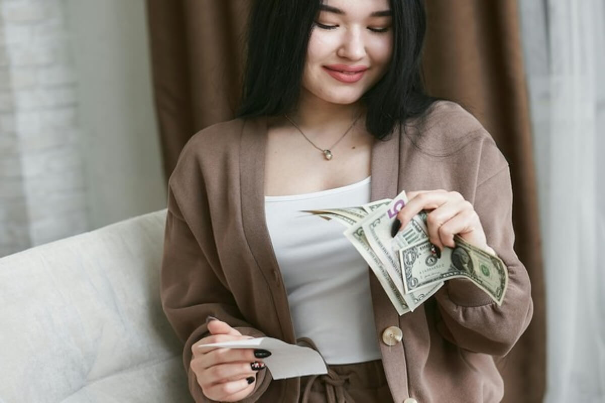 Woman counting cash with a smile, highlighting smart spending, budgeting and money lessons for managing personal finances wisely.