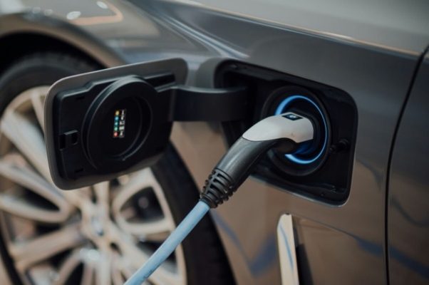 Electric vehicle charging at a public charging station, illustrating charging costs and EV ownership.