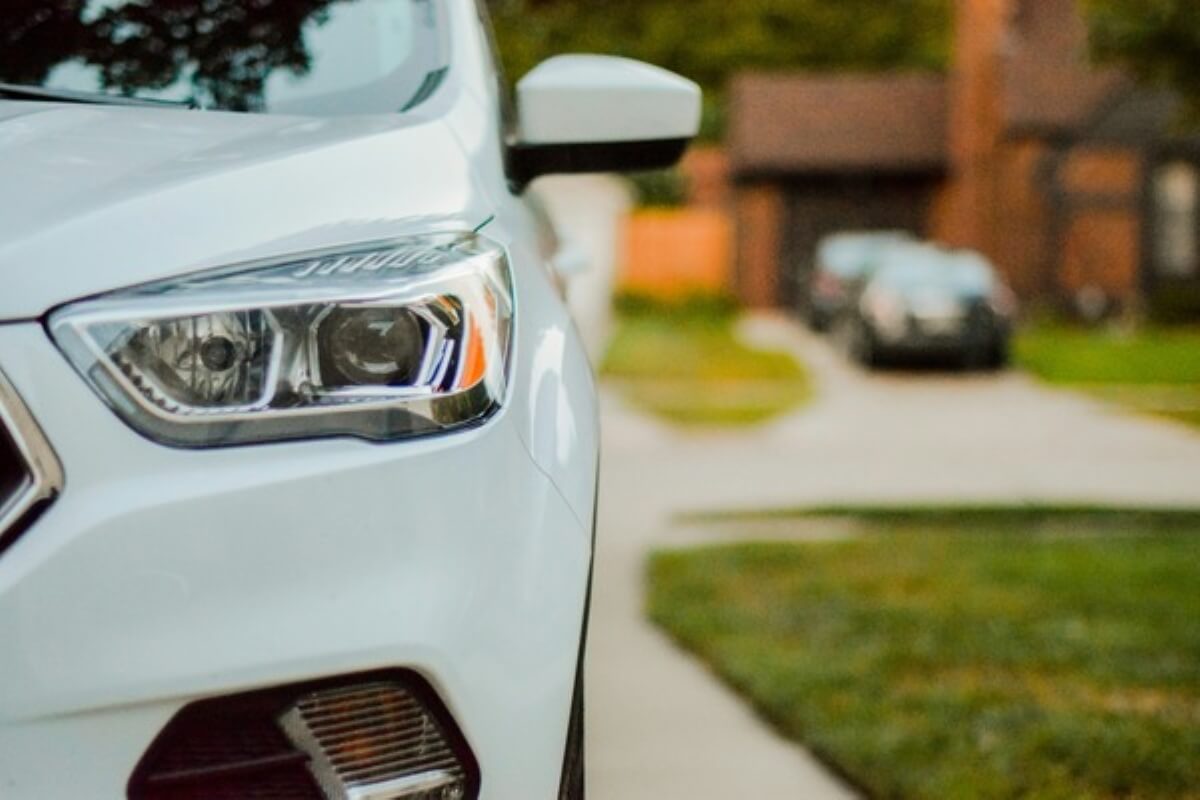 Front view of a parked white car, representing the growing adoption of electric vehicles and car ownership costs.