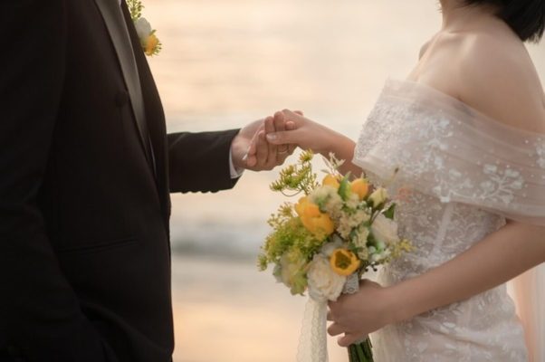 Bride and groom holding hands during their wedding ceremony, highlighting the importance of managing debt together as newlyweds.