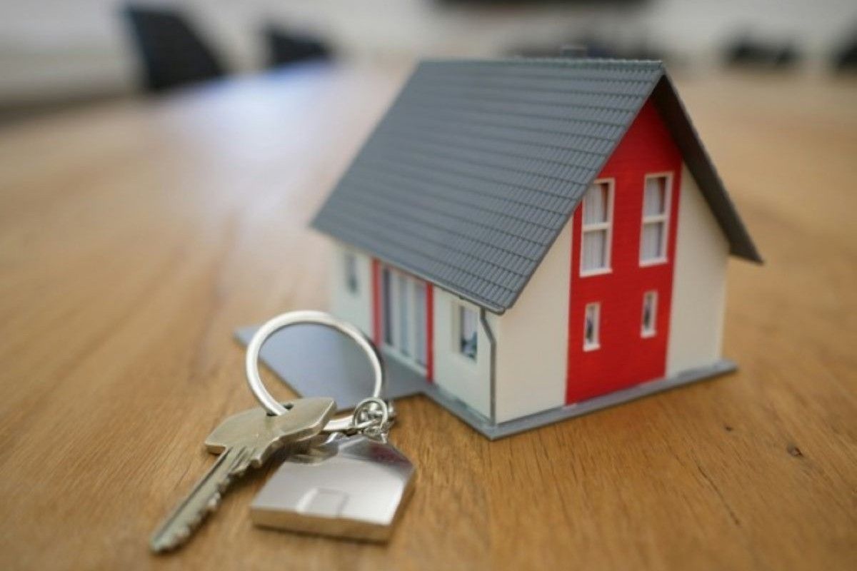 House model and keys on a table, representing homeownership goals achieved by managing debt and maintaining healthy finances.