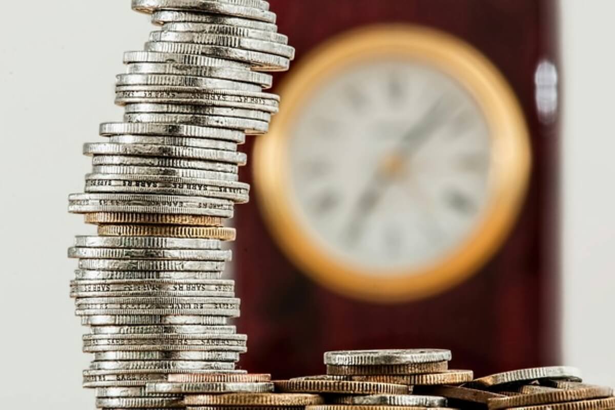 Stacks of coins beside a clock, showing how time and compound growth can help make your child a millionaire.
