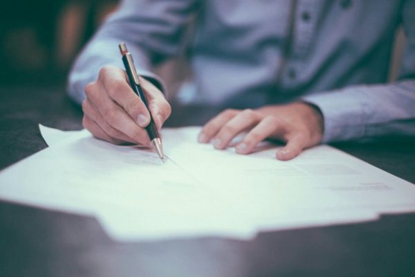 Professional signing an employment contract after successfully negotiating the job offer and agreeing on key employment terms.