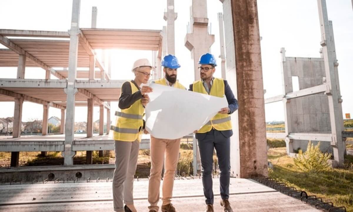 Engineers reviewing building plans at a construction site, demonstrating due diligence before buying property under construction.
