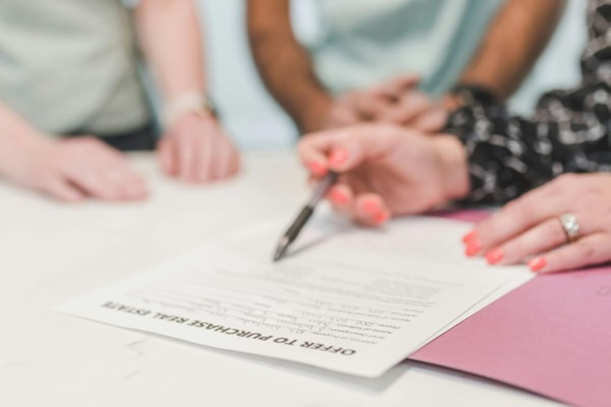 Buyer signing a purchase agreement with a property agent, representing the legal paperwork involved in buying property under construction.