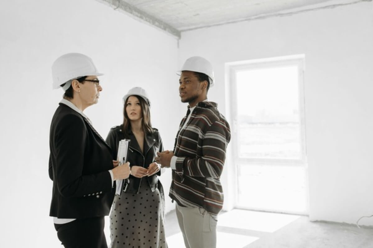 Property consultant discussing an unfinished home with prospective buyers during a site inspection for buying property under construction.