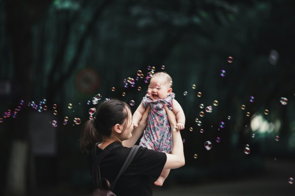 Mother lifting her baby outdoors, symbolising family-friendly measures that support working mothers in Singapore.