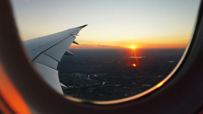 Airplane wing viewed at sunset, representing how travellers can use rewards and points to enjoy free travel.