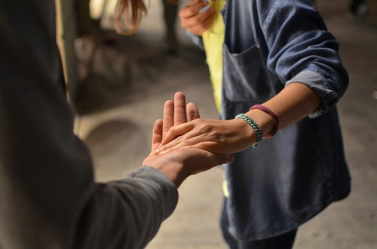 Traveller receiving help from another person, highlighting volunteering and work-exchange opportunities for free travel.