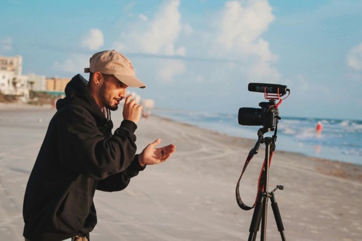 Travel creator filming on a beach, showing how content creation and sponsorships can support free travel.