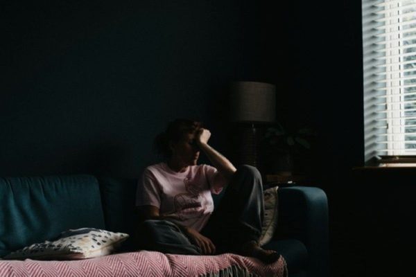 Person sitting alone in a dark room while struggling with imposter syndrome.