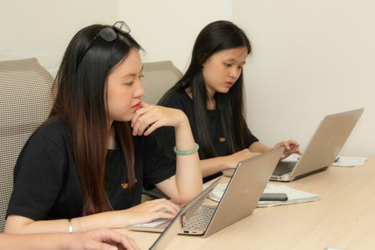 Two women working on laptops while discussing retirement planning and career breaks.