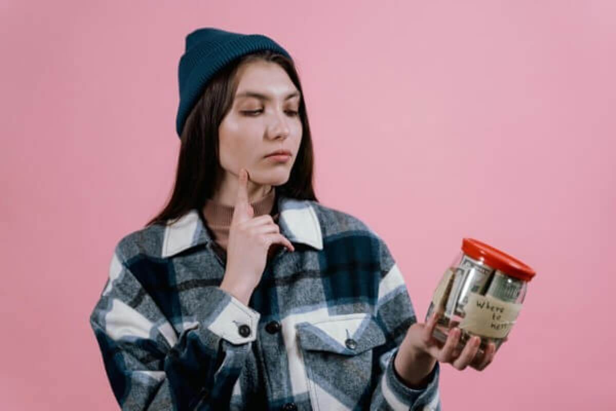 Woman holding a savings jar while reviewing retirement planning for future breaks.