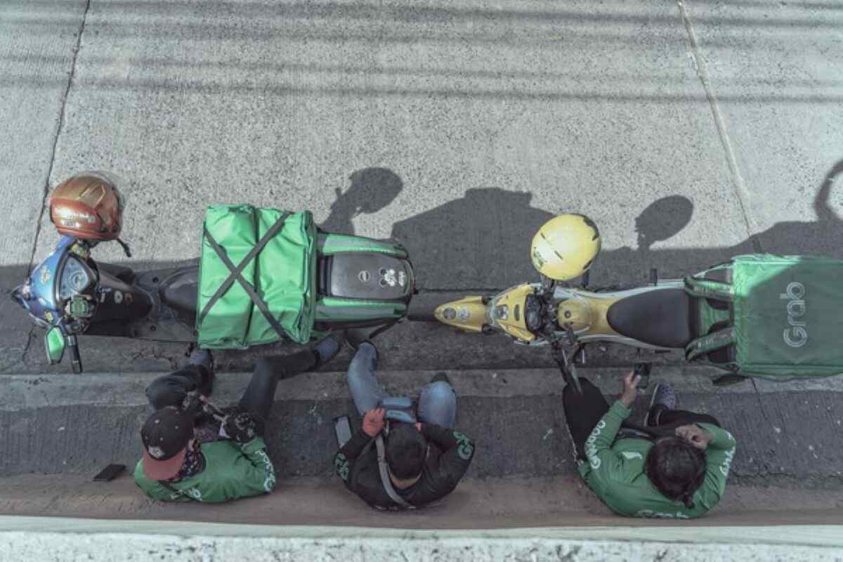 Grab delivery riders waiting beside their motorcycles, illustrating a Singapore company pursuing a SPAC IPO overseas.