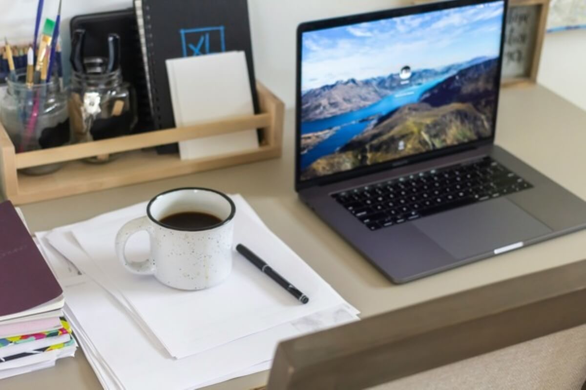 Laptop, paperwork and coffee on a desk for planning an HDB renovation budget.