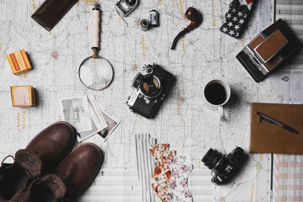 Travel essentials including cameras, maps, passport holder, and coffee, highlighting the benefits of a travel credit card for frequent travellers.