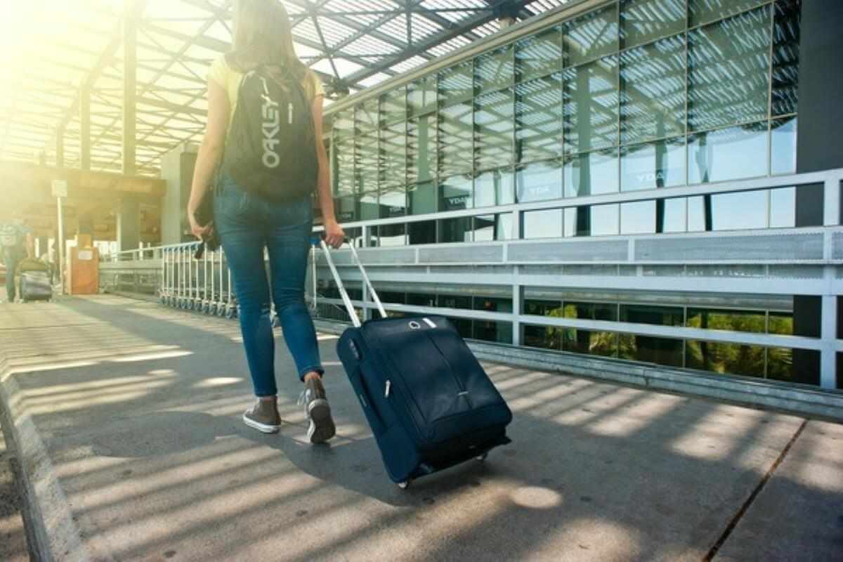 Traveller pulling a suitcase through an airport, highlighting the importance of health insurance singapore before overseas trips.