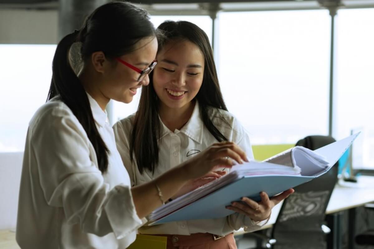 Two young professionals reviewing financial documents and discussing strategies to prepare for trump tariff.